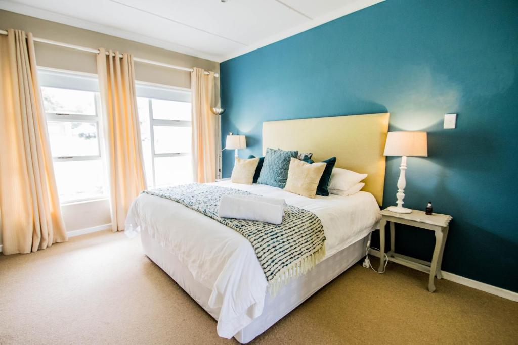 1 dormitorio con 1 cama con pared azul en Die Strandhuis - Stilbaai, en Stilbaai