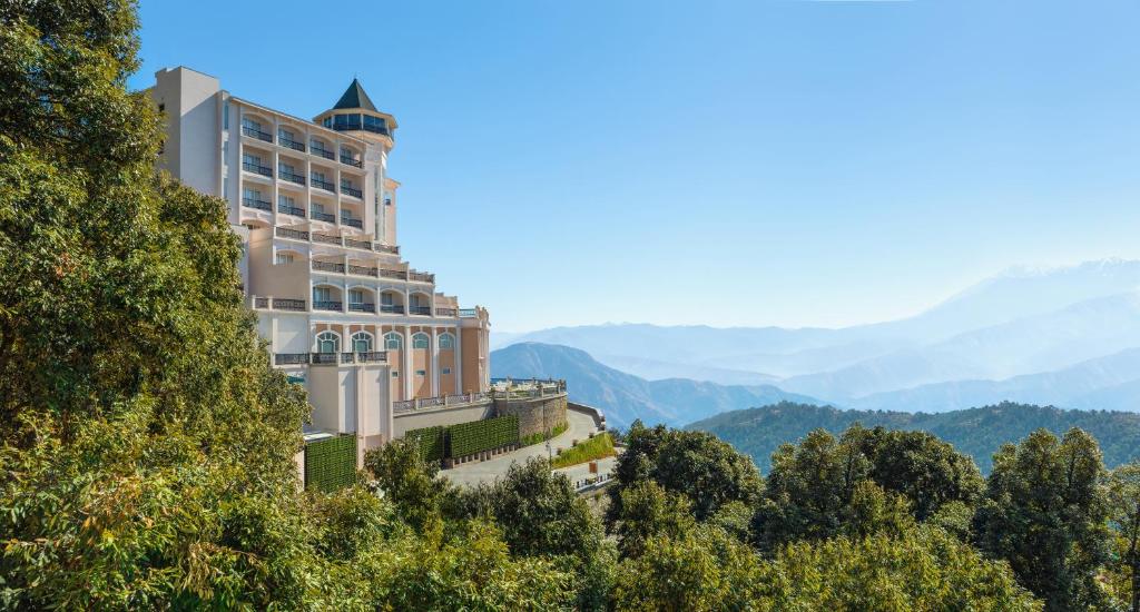 a building on a hill with mountains in the background at Welcomhotel by ITC Hotels, Tavleen, Chail in Chail