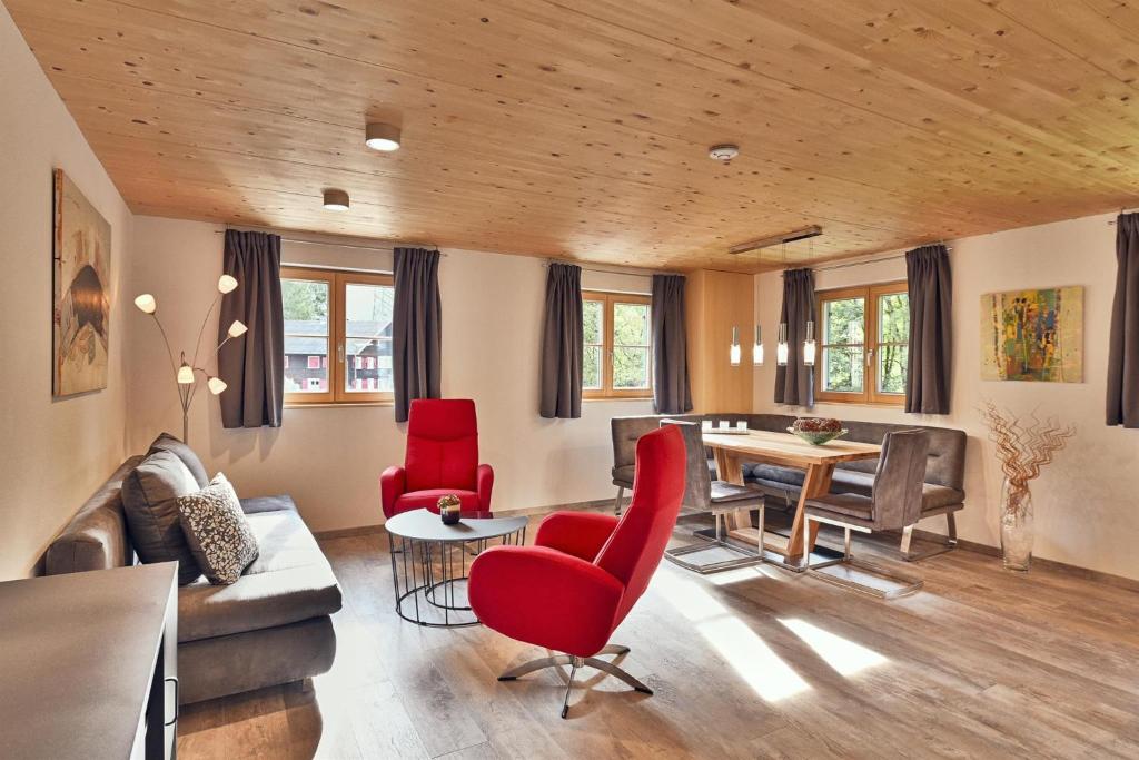 a living room with red chairs and a table at Arlberg Öko Ferienwohnungen in Innerbraz