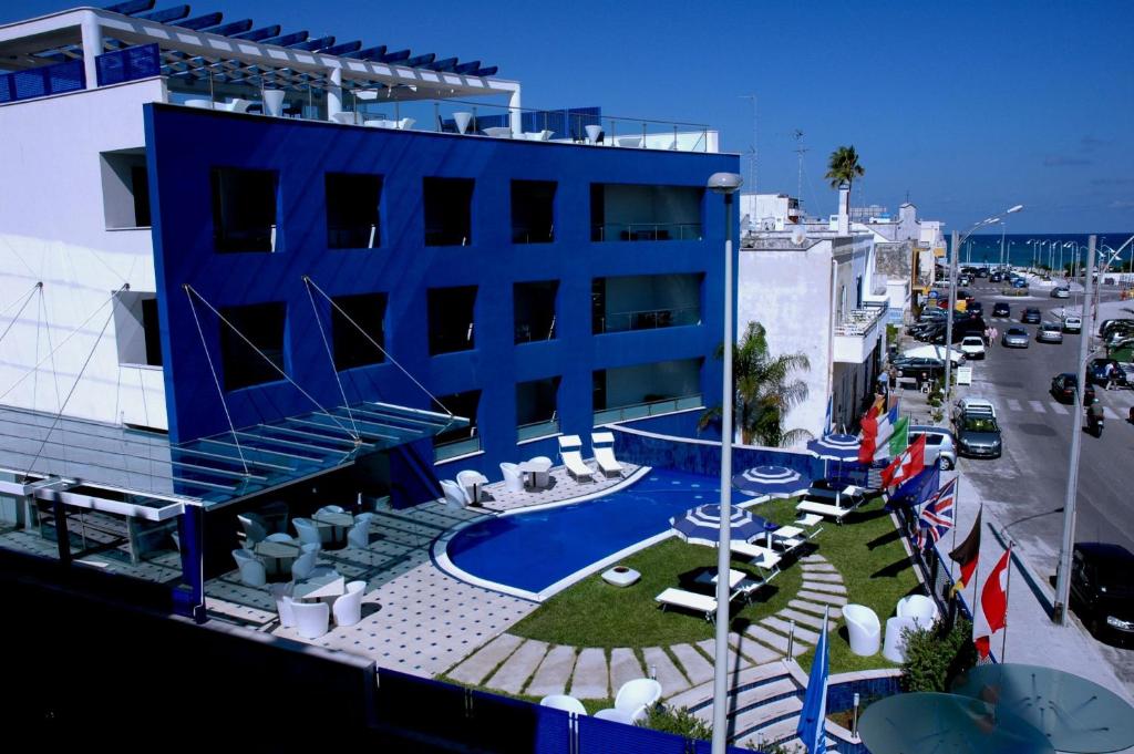 a blue building with a swimming pool next to a street at Hotel Côte D'Est in San Foca
