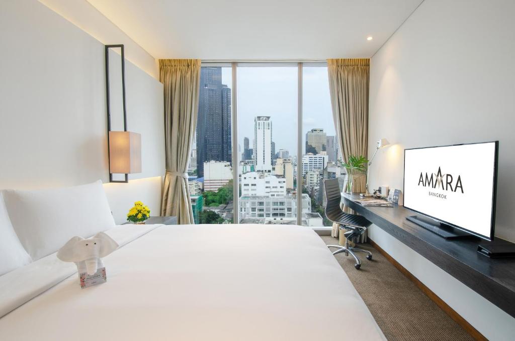 a hotel room with a large bed and a flat screen tv at Amara Bangkok Hotel in Bangkok