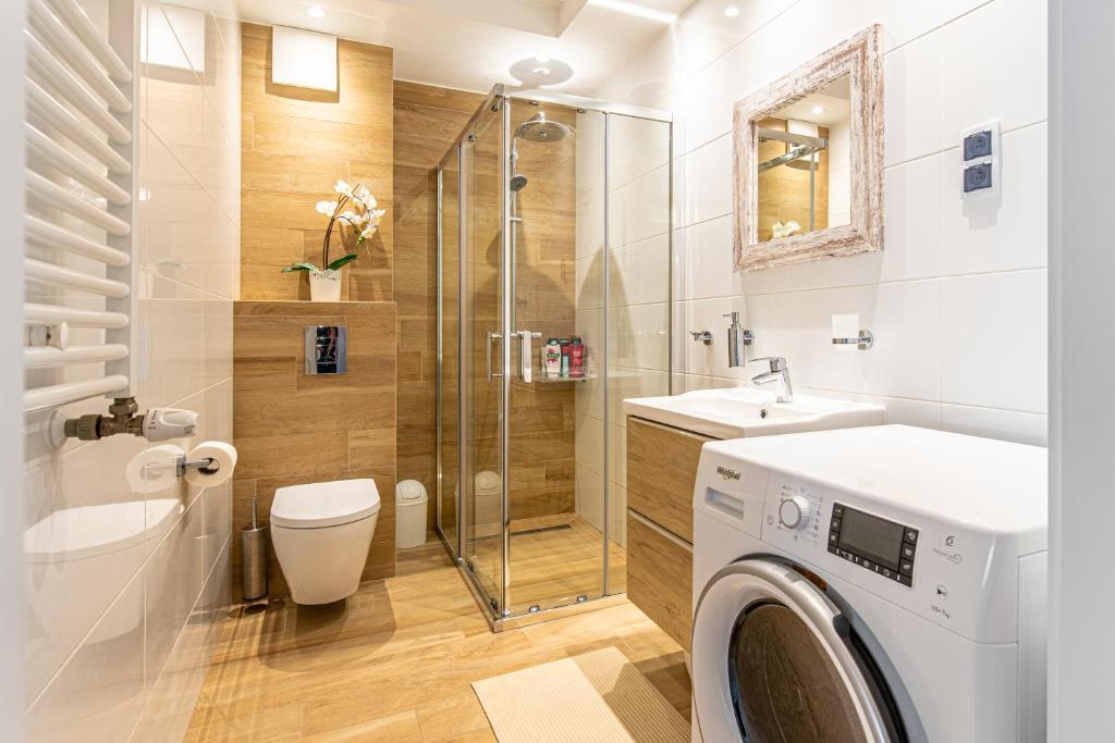 a bathroom with a shower toilet and a washing machine at Bella Casa Premium Apartment - 30 Pszczelna in Krakow