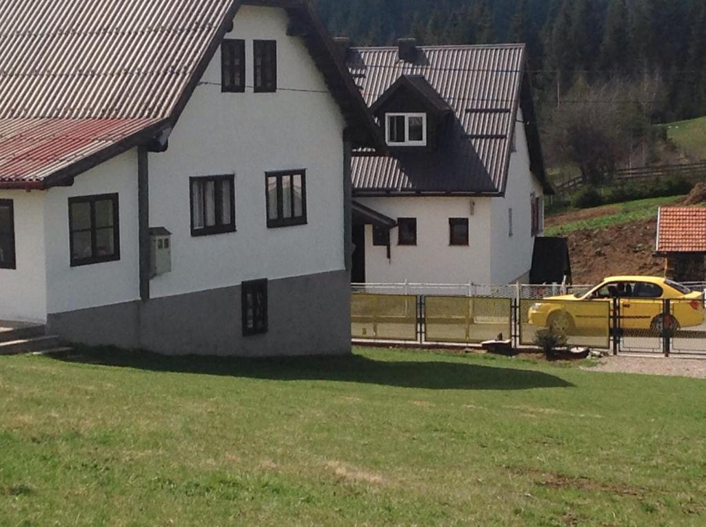 a yellow car parked in front of a white house at Apartments Baba Luce in Strica