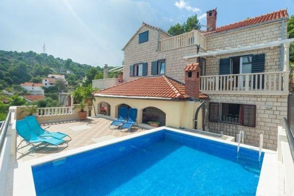 a house with a swimming pool and two blue chairs at Holiday Home with Pool (4298) in Postira