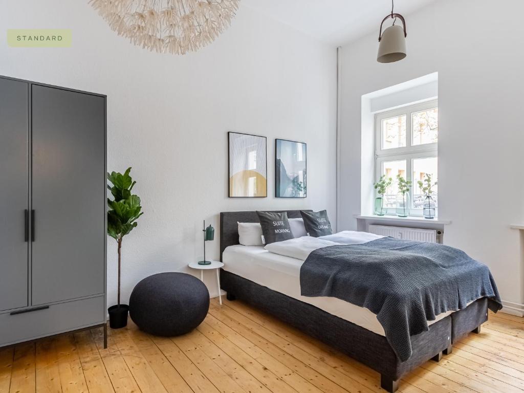 a white bedroom with a bed and a chandelier at Apartments Berlin Niederbarnimstraße in Berlin