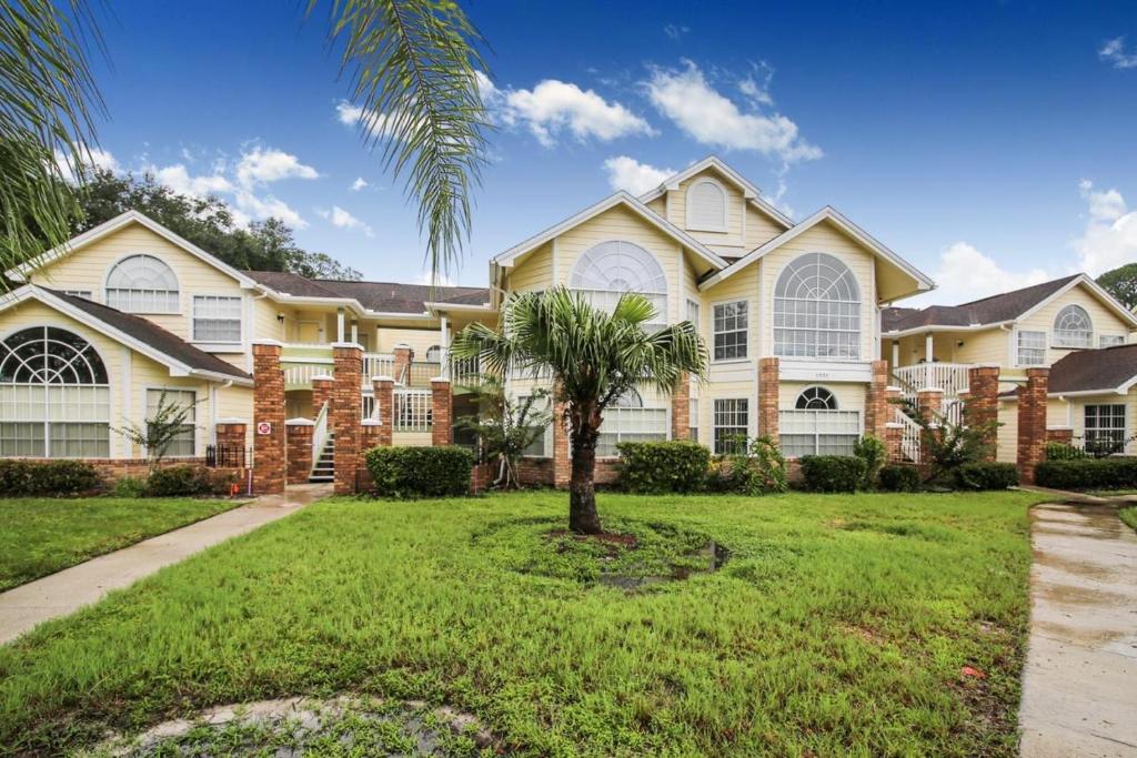 a large house with a palm tree in the yard at Grand Family 3BD Condo Apartment near Disney Parks #5 in Kissimmee