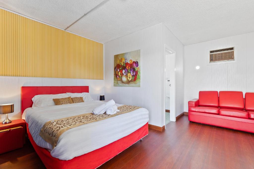- une chambre avec un grand lit et un canapé rouge dans l'établissement Albion Motel Finley - Best Rates in Town, Short & Extended Stays, à Finley