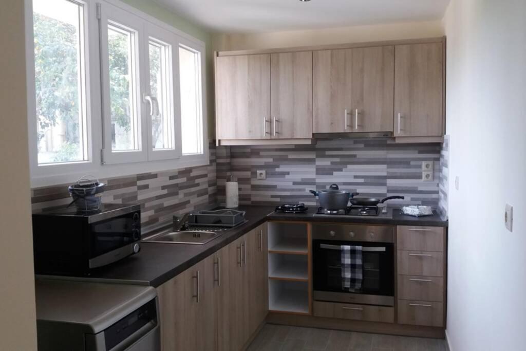 a kitchen with wooden cabinets and a counter top at Nafsika House Benitses in Benitses