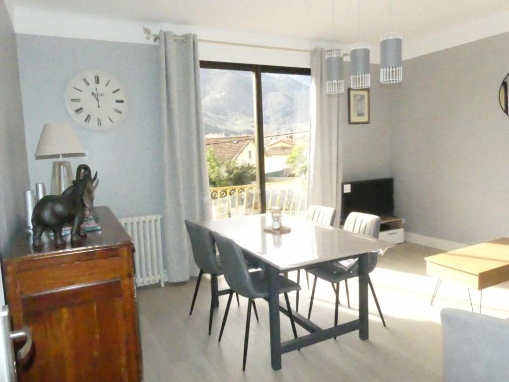 uma sala de jantar com mesa e cadeiras e um relógio em BEL APPARTEMENT TYPE F3 em Amélie-les-Bains-Palalda