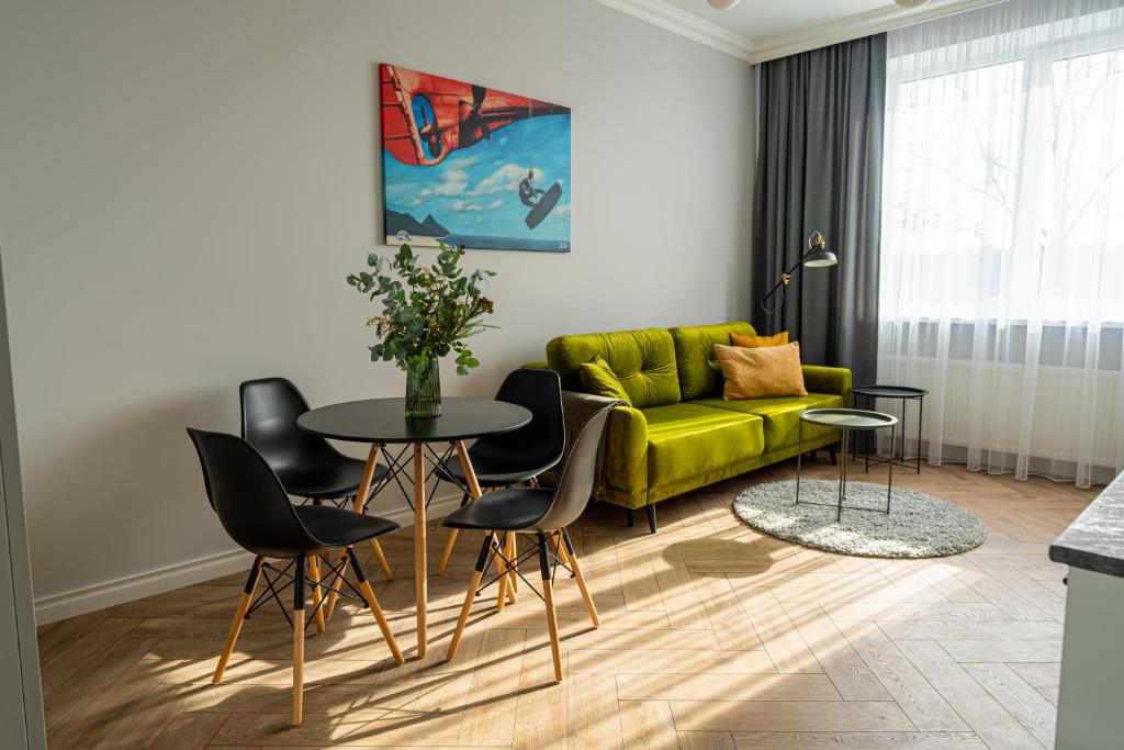 un soggiorno con divano verde, tavolo e sedie di Wonderful Apartment In The Heart Of Kaunas Center a Kaunas