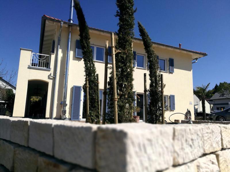 una casa con árboles frente a un muro de piedra en Ferienwohnung A Casa Mia, en Gengenbach