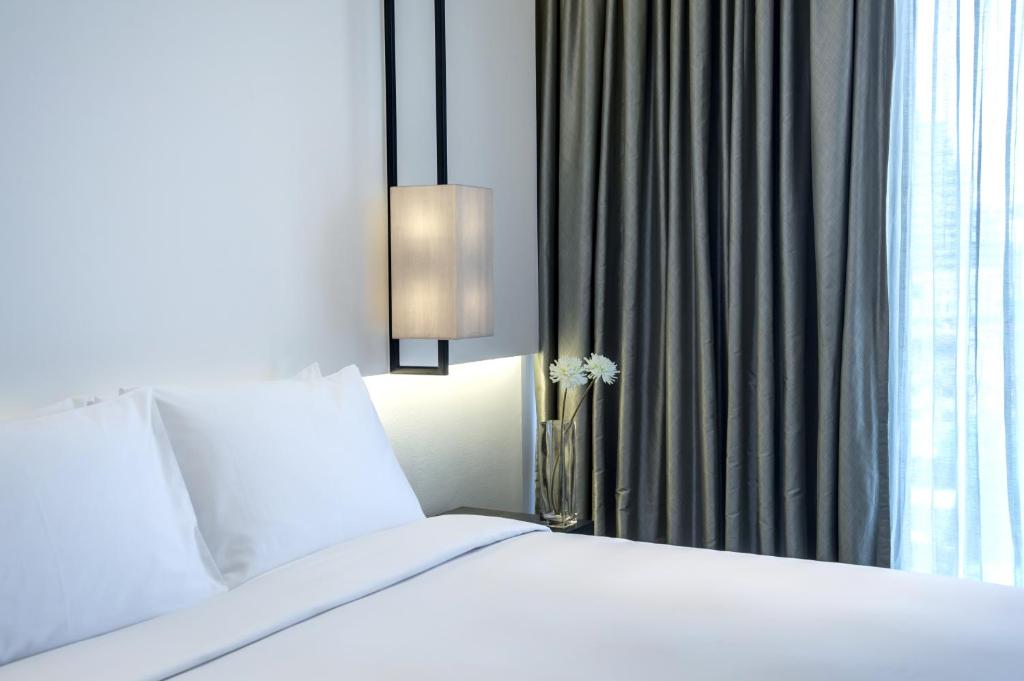 a bedroom with a white bed and a window at Amara Bangkok Hotel in Bangkok