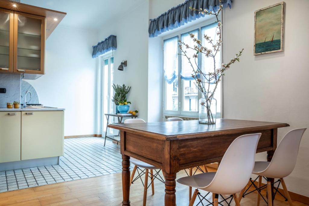 cocina y comedor con mesa de madera y sillas blancas en Appartamento La Vela, en San Bartolomeo al Mare