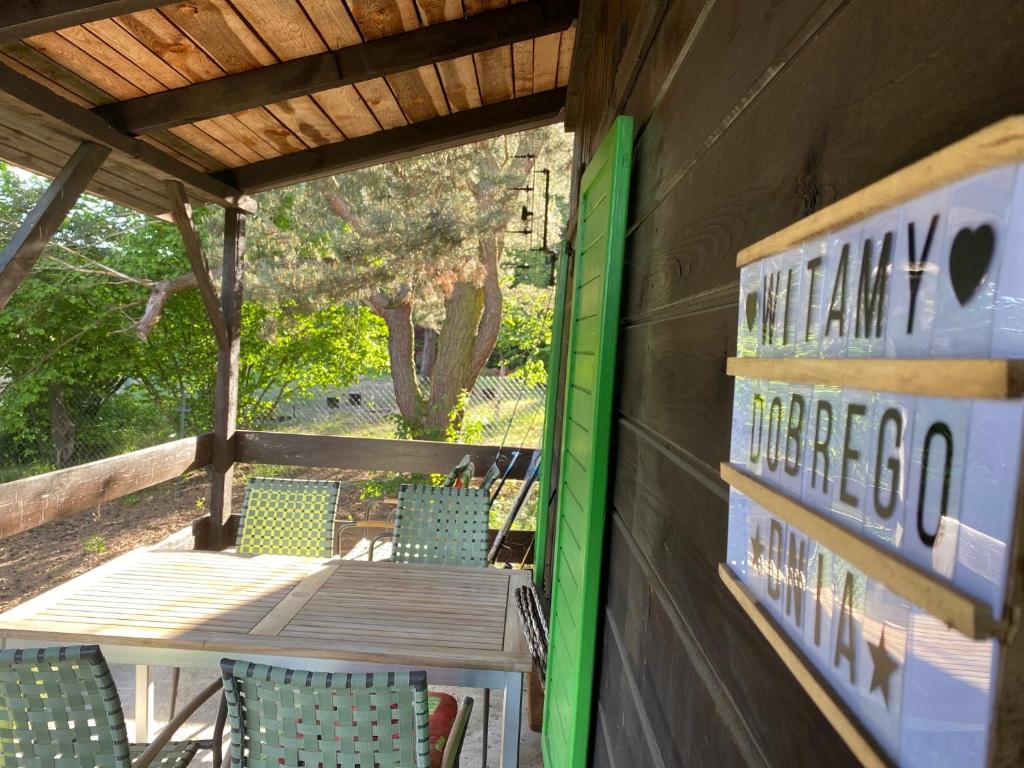 een houten veranda met een tafel en stoelen op een terras bij Dom Pod Sosnami in Rzewnie