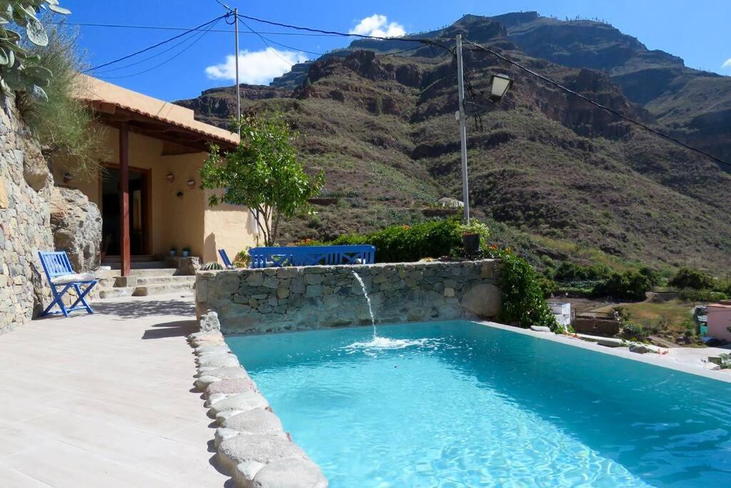 a swimming pool with a waterfall in front of a mountain at Casa con piscina privada en Cercados de Espino in Las Casillas