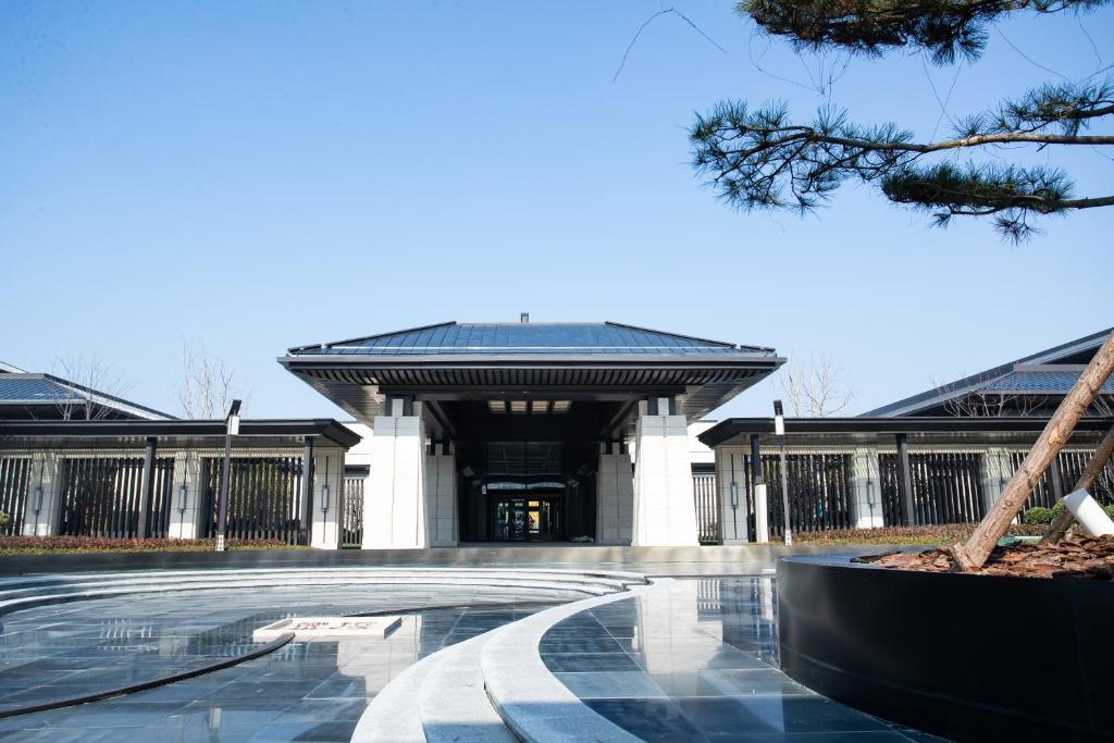 a building with a black roof and a walkway at Primus Hotel Xuzhou Dalong Lake in Xuzhou