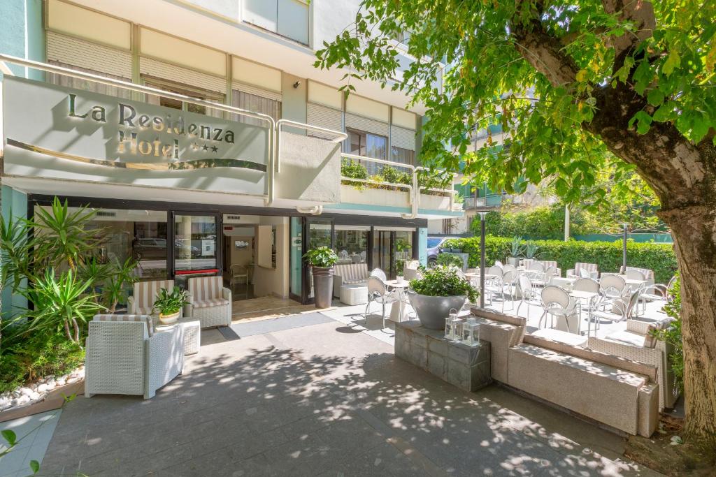 a patio with white chairs and a building at Hotel La Residenza in Riccione