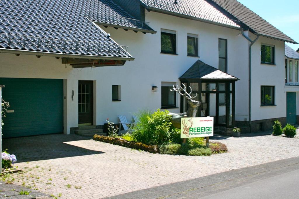 a house with a garage and a sign in front of it at Eifel REBEIGE Gerolstein in Kopp