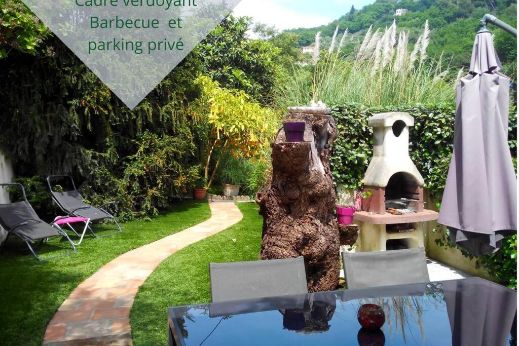 een tuin met een tafel en een parasol bij L'Annexe in Menton