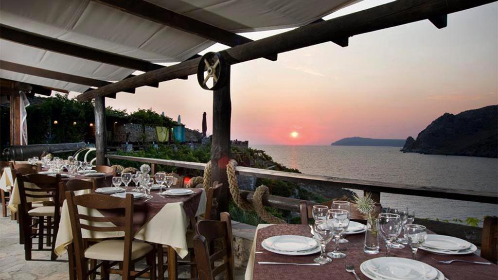 a restaurant with tables and chairs with a view of the ocean at Marmari Paradise Resort Hotel in Marmari