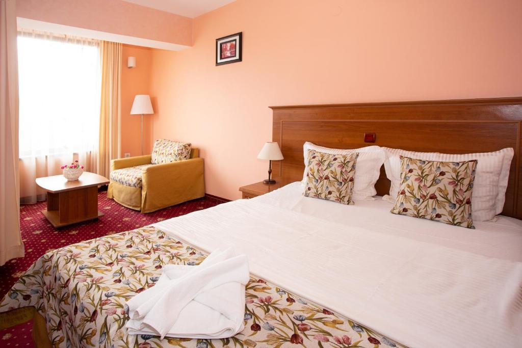a hotel room with a large bed and a chair at Contessa Hotel in Shumen