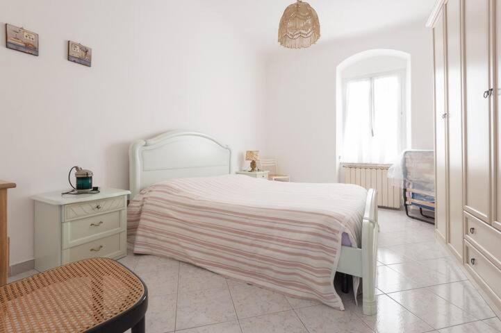 a white bedroom with a white bed and a chair at Casa a Lerici nell'antico borgo in Lerici