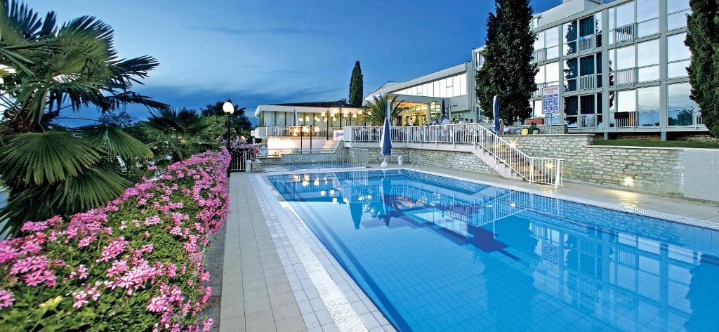 a swimming pool with flowers in front of a building at Hotel Zorna Plava Laguna in Poreč