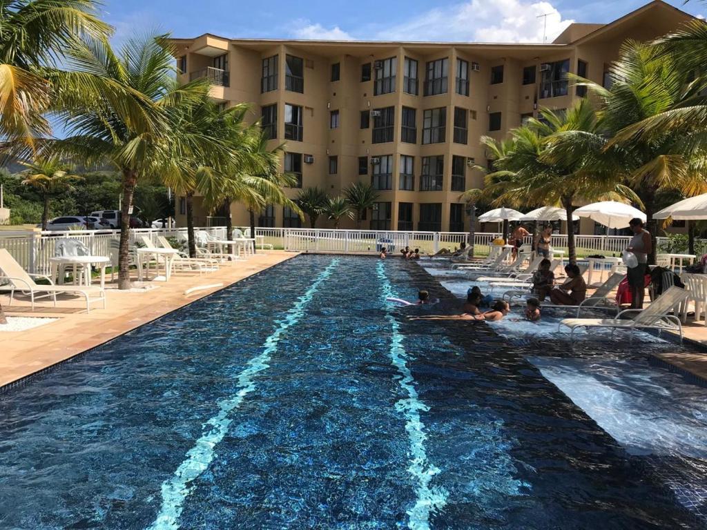 een zwembad in een resort met mensen erin bij Loft Sahy - Condado Aldeia dos Reis in Mangaratiba
