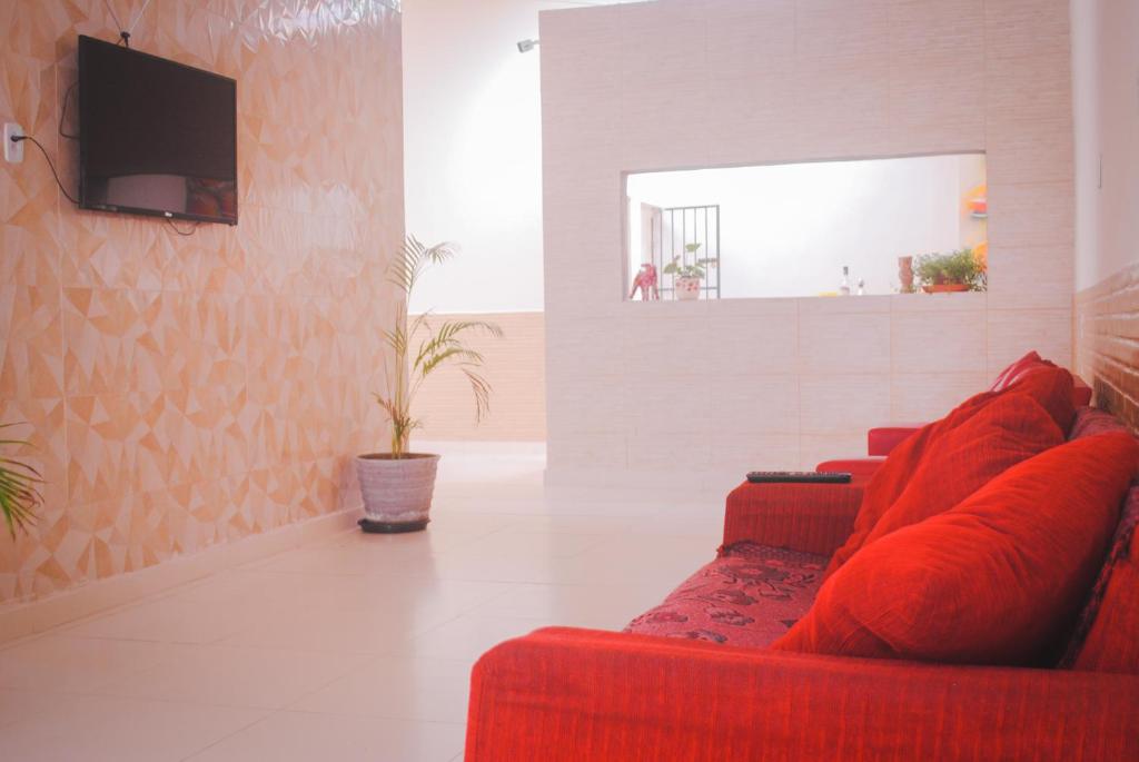 a living room with a red couch and a tv at Hotel Paradiso in João Pessoa