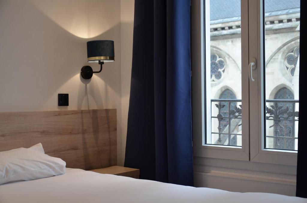 a bedroom with a bed and a window at Hôtel De La Perdrix Rouge in Paris