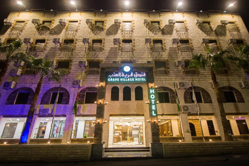 un edificio con un cartel en él por la noche en Grape Village Hotel en Amán