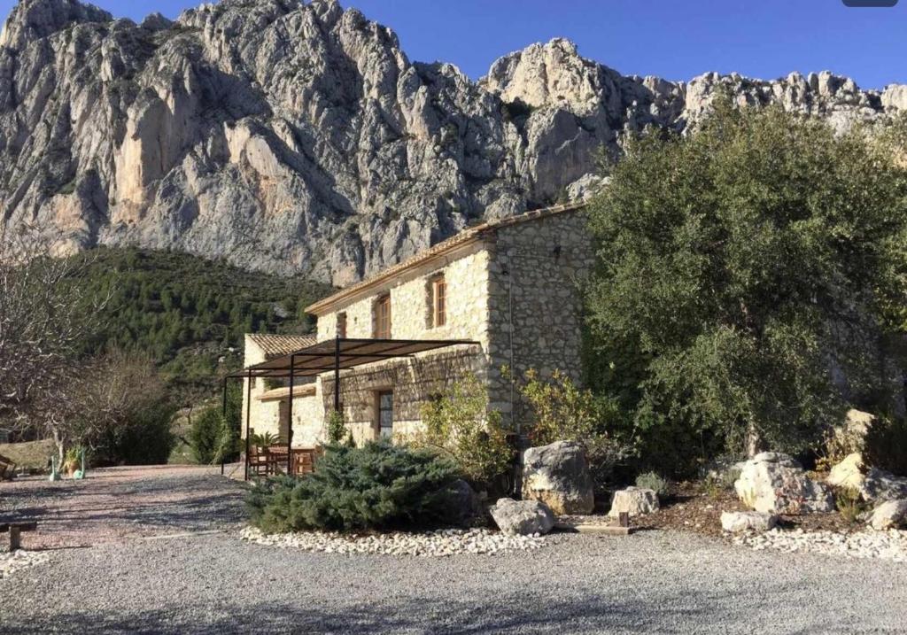 a stone building with a mountain in the background at Torre de Arriba Casa Rural in Benimantell
