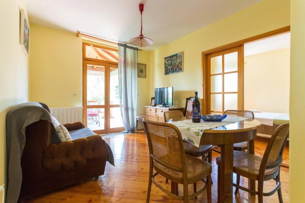 een woonkamer met een tafel en stoelen en een bank bij Sleep & Fly Cottage in Čilipi