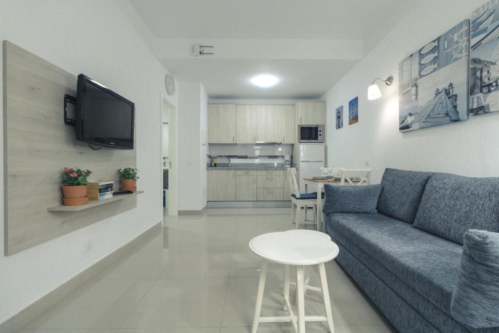 a living room with a couch and a table and a kitchen at Puerto Mogan Apartment in Puerto de Mogán