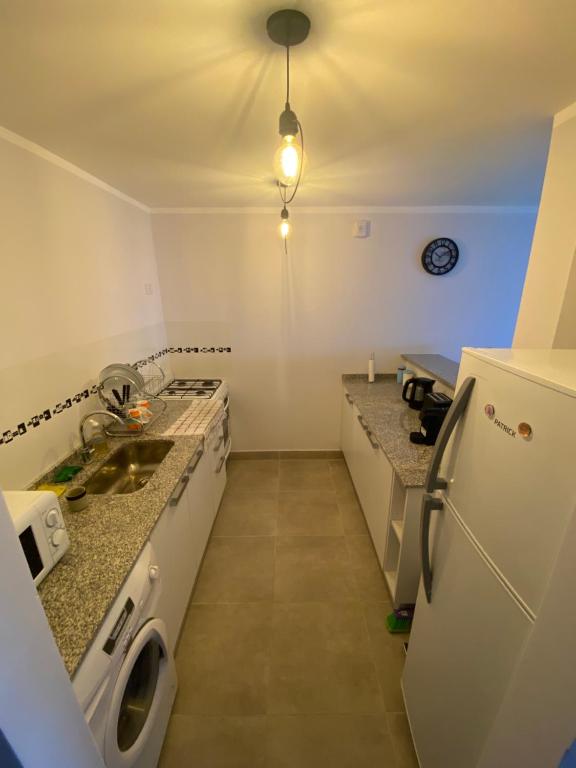 una pequeña cocina con fregadero y nevera. en TIERRA Alojamientos en Salta