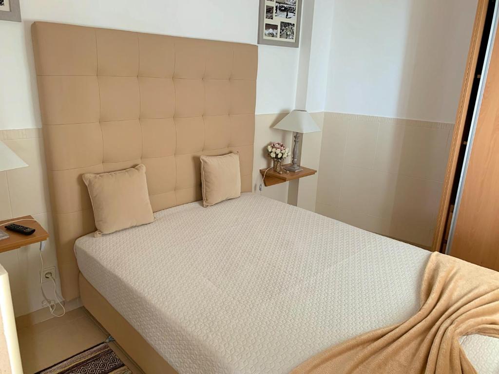 a small bedroom with a bed and two pillows at Duarte Houses - Casa T1 - com vista mar in Nazaré