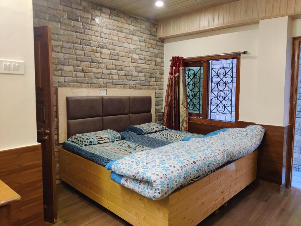 a bed in a room with a brick wall at Mehdudia Guest House in Shimla