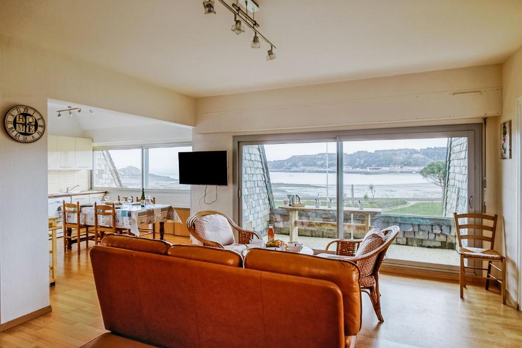 een woonkamer met een bank en een tafel en stoelen bij Ker Paul et Ker Julien- appartements vue mer in Erquy