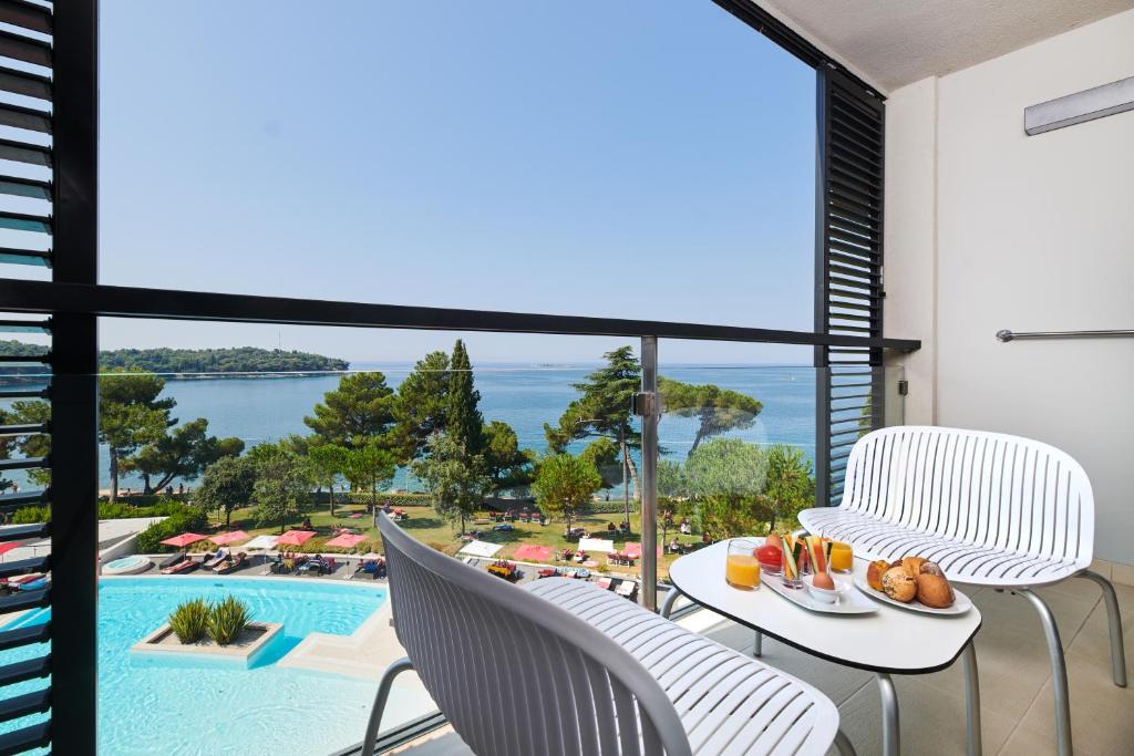 a balcony with a table and chairs and a pool at Hotel Parentium Plava Laguna in Poreč