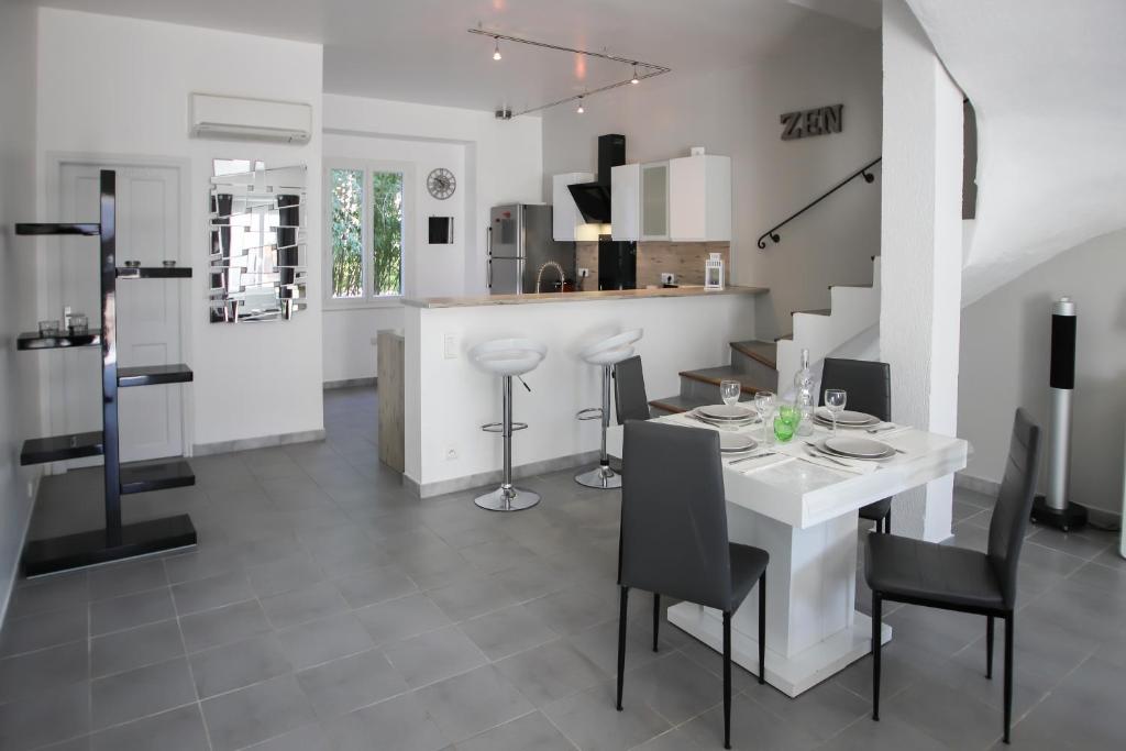 a kitchen and dining room with a white table and chairs at Maison tendance avec jardin, centre village, Alpilles, familles in Eyragues
