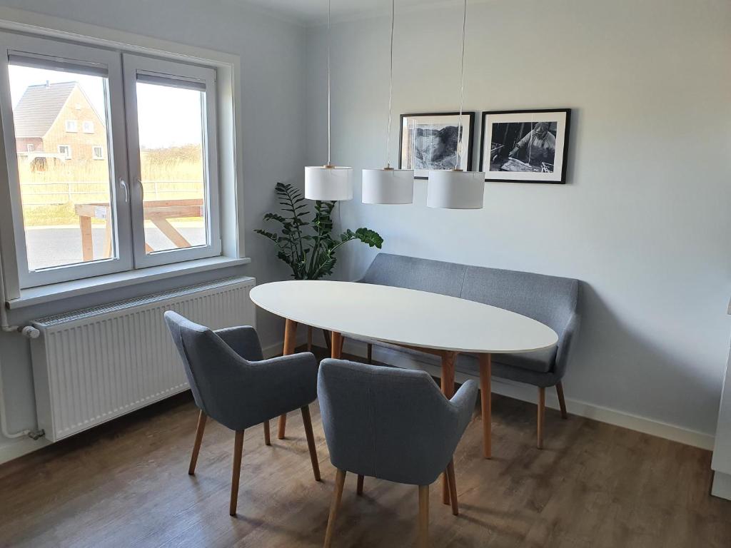 une salle à manger avec une table et des chaises blanches dans l'établissement Ferienwohnung Südwesthörn, à Emmelsbüll-Horsbüll