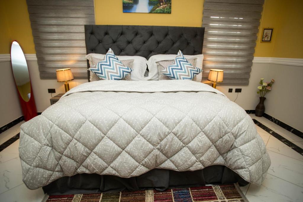 a bedroom with a large bed with a gray comforter at Brynx Haven - Cape Coast in Cape Coast