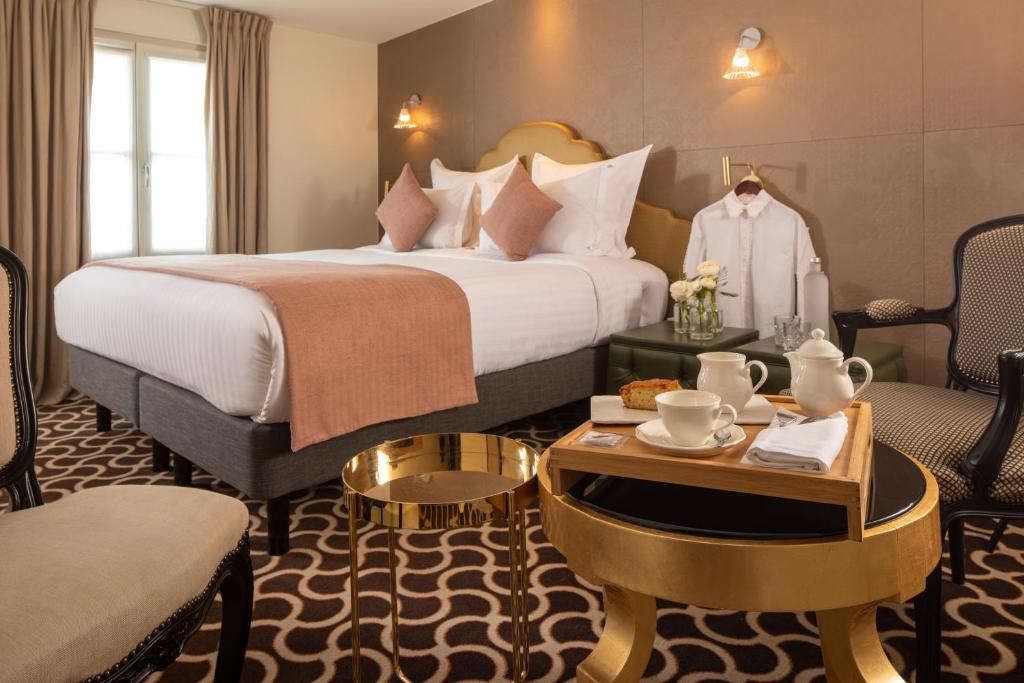 une chambre d'hôtel avec un lit, une table et des chaises dans l'établissement Le Pradey, à Paris