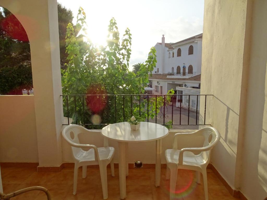 d'une table blanche et de deux chaises sur un balcon. dans l'établissement Aldeas Taray Admer 14, à La Manga del Mar Meno