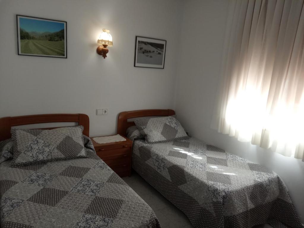 1 dormitorio con 2 camas y ventana en Casa Nando, en Esterri d'Àneu