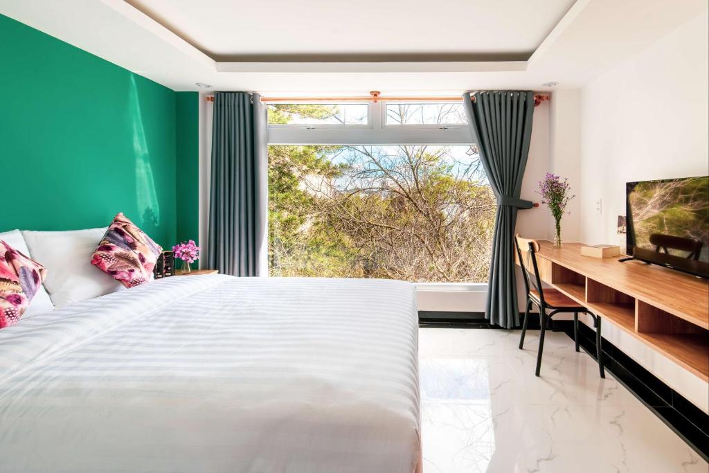 大叻的住宿－Hoa Mi Condotel，一间卧室配有一张床、一张书桌和一个窗户。