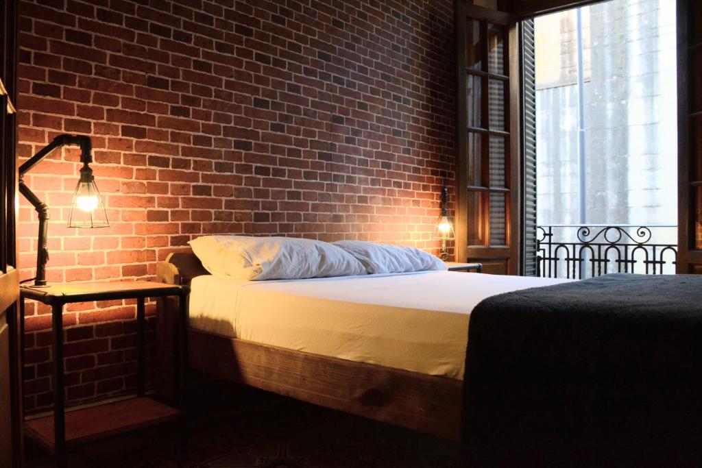 Ce lit se trouve dans une chambre dotée d'un mur en briques. dans l'établissement 531 Hostel, à Córdoba