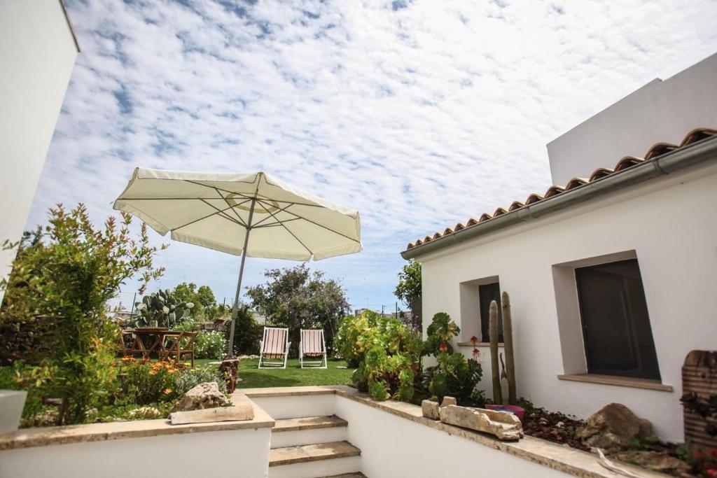 - une terrasse avec un parasol et des chaises dans l'établissement Casa Aquilino, à Patù