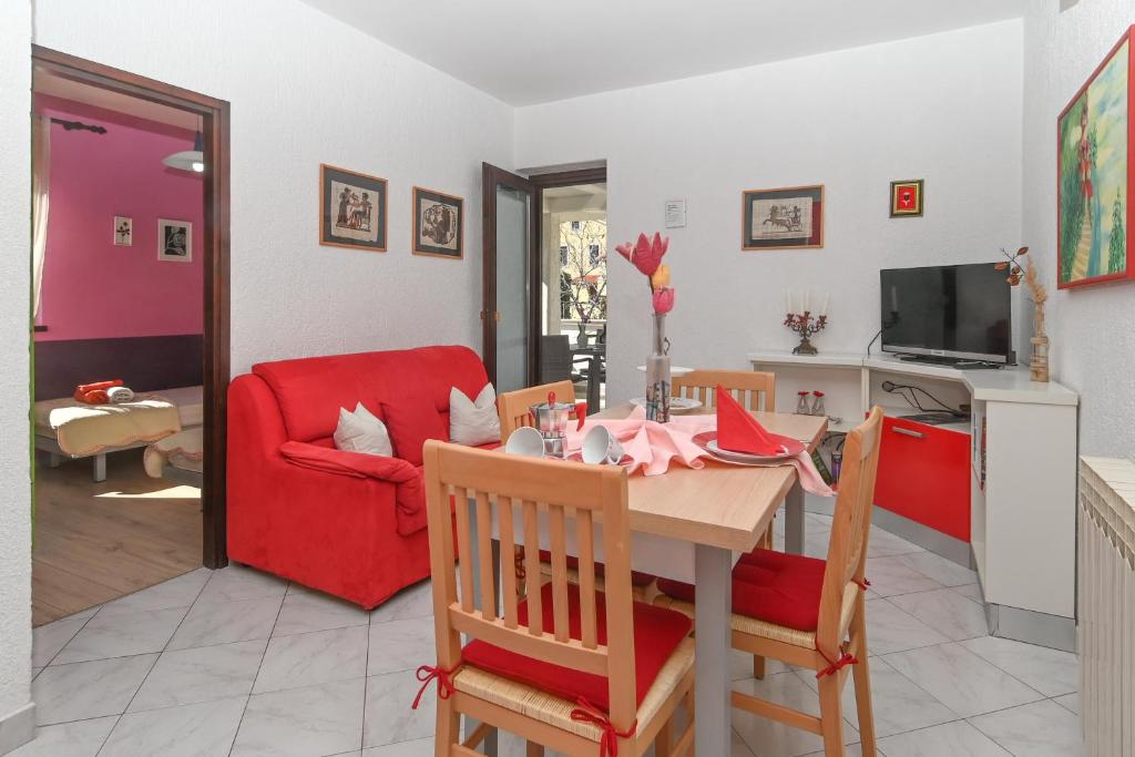 a living room with a table and a red couch at Apartments Sunčica in Mali Lošinj