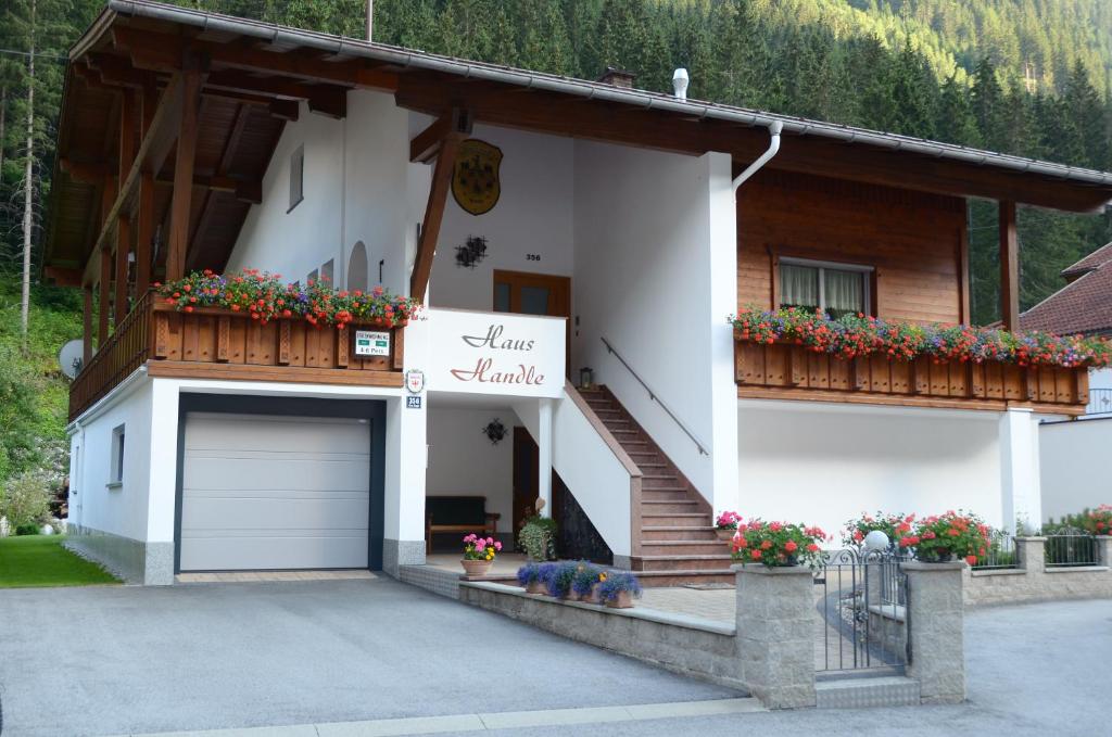 a white house with a garage and flowers in front at Haus Handle in Kappl